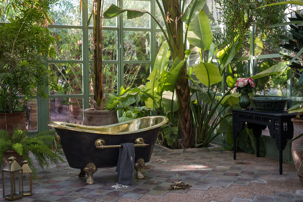 Brass bathtub on claw feet with a blackened exterior.